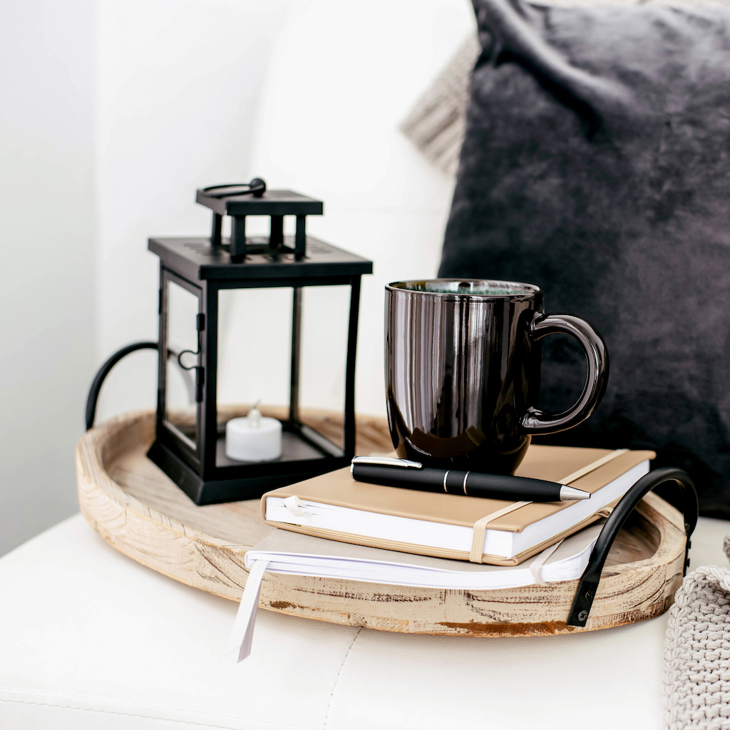 A tray with a cup of coffee and a notebook on it.